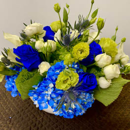 Blue and white floral arrangement with yellow accents in a white bowl