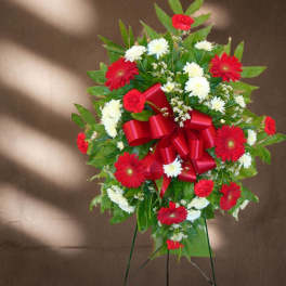 Standing spray of red and white daisies with a red ribbon bow