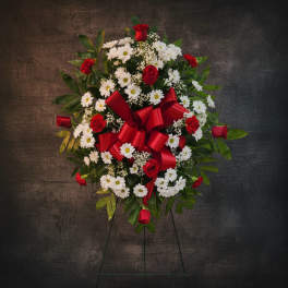 Standing floral wreath with red roses, white daisies, and a red ribbon bow