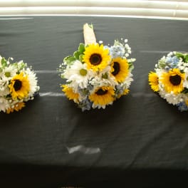 Three sunflower and daisy bouquets with wrapped handles