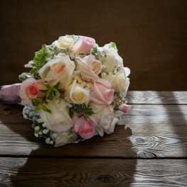 Bouquet of pale pink and white roses on a wooden table