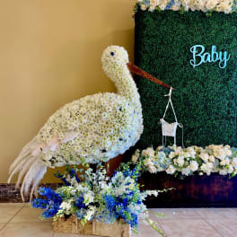 White floral swan display beside a green backdrop with blue flowers