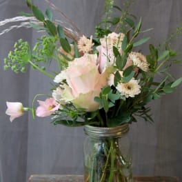 Pink roses and white daisies arranged in a glass jar vase