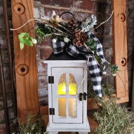 Decorative lantern with pinecones, plaid ribbon, and greenery