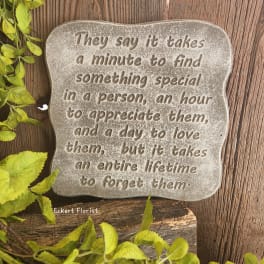 Decorative stone plaque with a quote on a wood background