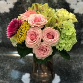 Mixed bouquet of pink roses, hydrangea, and yellow flowers in a vase