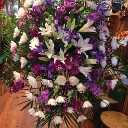 Large standing floral spray with white lilies, purple irises, and pink blooms