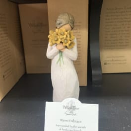 Figurine in a white dress holding a bouquet of yellow flowers