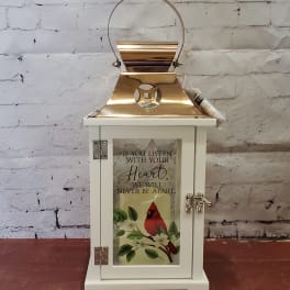 White decorative lantern with a gold top and a cardinal design on the front