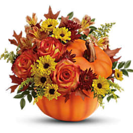 Autumn floral arrangement in a pumpkin container with roses and daisies