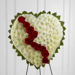 Heart-shaped standing spray of white flowers with a diagonal line of red roses