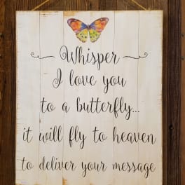 Wooden memorial sign with a colorful butterfly and the words "Whisper I love you"