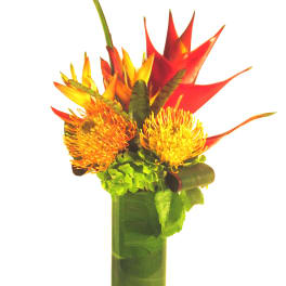 Tall tropical arrangement with orange and yellow blooms in a leaf-lined glass cylinder vase