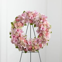 Pink floral wreath with lilies, roses, and carnations on a metal easel