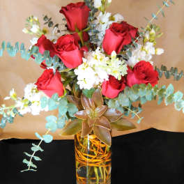 Tall vase arrangement with red roses, white flowers, eucalyptus, and a large succulent.