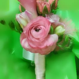 Small handheld bouquet of pink flowers with a wrapped handle on a bright green background