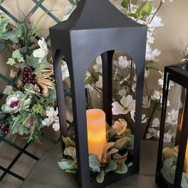 Black lantern with a glowing candle and white floral accents