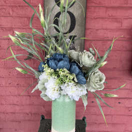 Blue and white floral arrangement in a tall mint vase