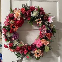 Floral wreath with pink, red, and peach blooms on a door