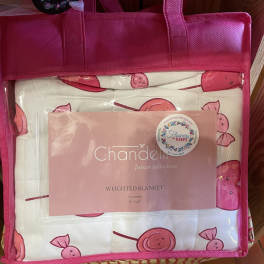 Pink tote bag holding a packaged weighted blanket with cherry print