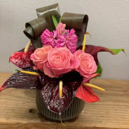 Pink roses and magenta flowers arranged in a small vase