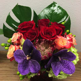 Bouquet of red and peach roses with purple orchids in a vase
