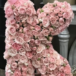 Pink rose teddy bear with pearl accents on a wooden base