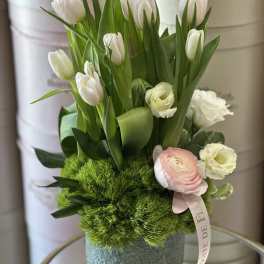 White tulips and pale pink blooms in a gray hatbox with green moss