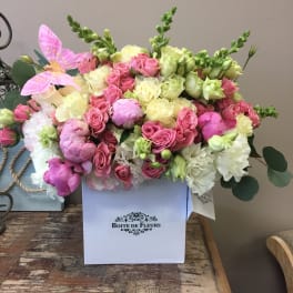Pink and cream roses arranged in a white box with a pink butterfly accent.