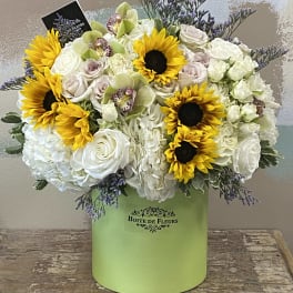 Mixed bouquet with sunflowers, white roses, and orchids in a green box