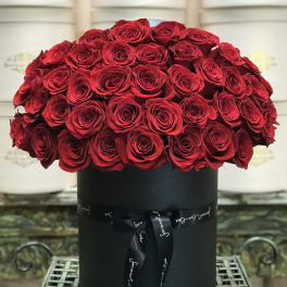Red roses arranged in a black round box with a ribbon