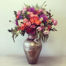 Mixed pink, purple, and orange flowers arranged in a metallic vase