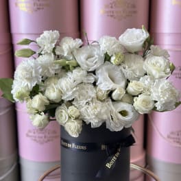 White roses and carnations arranged in a black hat box