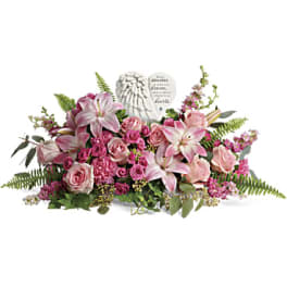 Pink lilies and roses arranged around a heart-shaped memorial stone