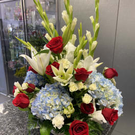 Red roses, white lilies, and blue hydrangeas in a basket arrangement