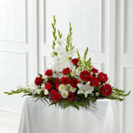 Red and white floral arrangement with tall white blooms on a draped table