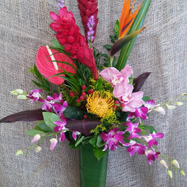 Tropical flower arrangement in a green vase with pink and orange blooms