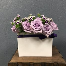 Lavender roses arranged in a white box with purple ribbon