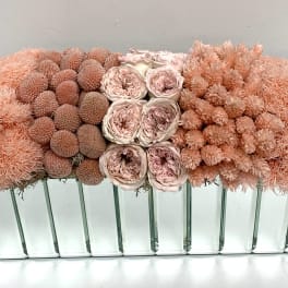 Peach and blush floral arrangement in a mirrored rectangular vase