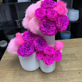 Bright pink floral arrangement in white vases with roses and fluffy blooms