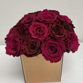 Bouquet of deep pink and burgundy roses in a square gold vase