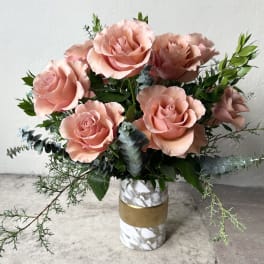 Pink roses arranged in a marble-pattern vase with greenery