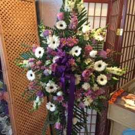 Tall standing floral spray with white and pink flowers and a purple ribbon