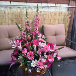 Pink mixed flower arrangement in a wicker basket