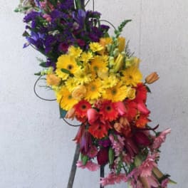 Tall colorful floral spray on a stand with yellow, purple, red, and pink blooms