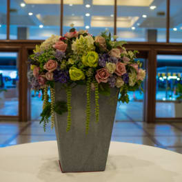 Mixed pink and green floral arrangement in a tall gray vase