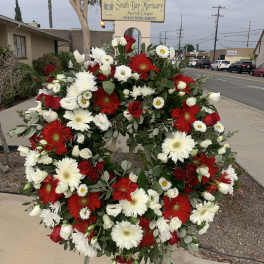 Large red, white, and green funeral wreath on a stand