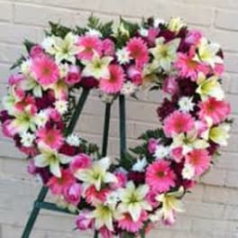 Heart-shaped floral wreath with pink and white flowers on a stand