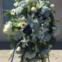 Blue and white funeral spray with lilies, hydrangeas, and ribbon
