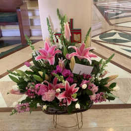 Large pink lily and orchid arrangement in a basket on a stand